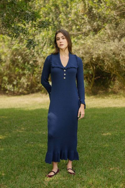 Romance Knit es un vestido maxi tejido de manga larga con una delicada composición de 30% baby alpaca, que ofrece calidez, suavidad y una caída impecable. Su punto acanalado estiliza la silueta, mientras que los bobos en mangas y basta aportan movimiento y un aire romántico.

El cuello estilo camisero junto a los tres botones de strass en el pecho añaden un toque sofisticado y luminoso, haciendo de esta pieza una elección perfecta para ocasiones especiales o para elevar un look de día con distinción.

Disponible en azul navy y gris, es una prenda versátil y atemporal que no pasará desapercibida.

La modelo usa talla XS/S.
