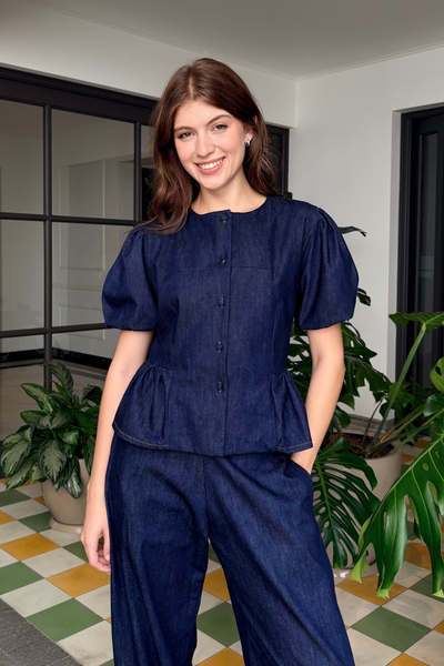 El Set Clara está compuesto por una jacket de manga corta y un pantalón de silueta semi barrel, creando un conjunto moderno y versátil. La jacket destaca por sus mangas abullonadas, botones frontales y un detalle de peplum que define sutilmente la cintura. Puede llevarse cerrada como blusa o abierta como sobrecamisa, permitiendo transformar el look según la ocasión.

El pantalón semi barrel aporta una silueta relajada y contemporánea, con una caída amplia que brinda comodidad y movimiento. El denim azul completa el conjunto con un estilo casual y sofisticado, ideal para crear un look coordinado o combinar cada pieza por separado.


	100% Algodón Pima.

