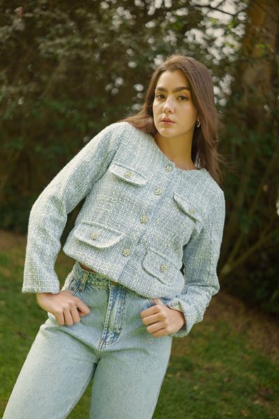 Twilight Tweed es un saco corto confeccionado en tela tweed mágica de color celeste, que aporta textura, luminosidad y un aire sofisticado. Su diseño incluye cuatro solapas de bolsillo en los laterales frontales y botones strass brillantes que capturan la luz y realzan la pieza.

Con forro interno para un acabado impecable, es una prenda versátil que eleva cualquier look, perfecta para combinar con faldas, vestidos o pantalones y lograr un estilo elegante con un toque moderno.

La modelo usa talla S
